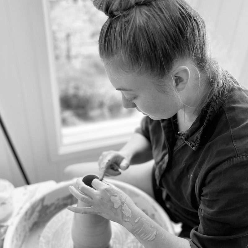 Reba Bawden at the wheel, centring clay, photographed in black and white