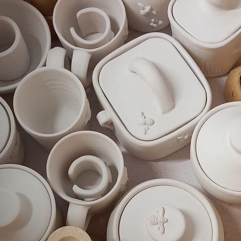 A kiln shelf packed with Sharon Oliver's unglazed pots — lidded jars, beakers and bowls in pale raw stoneware