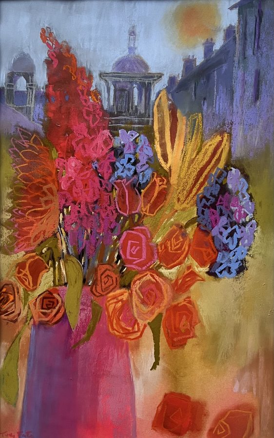 Poundbury — framed original pastel by Judy Tate, a vase of roses, delphiniums and hydrangeas in orange, pink and blue, with Poundbury's domed rotunda and pale classical facades softened behind
